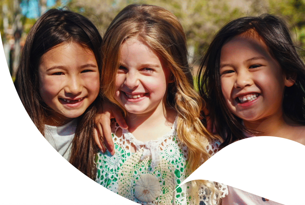Three smiling girls around primary school age. From the cover of the Brain Building in Queensland Years in Review
