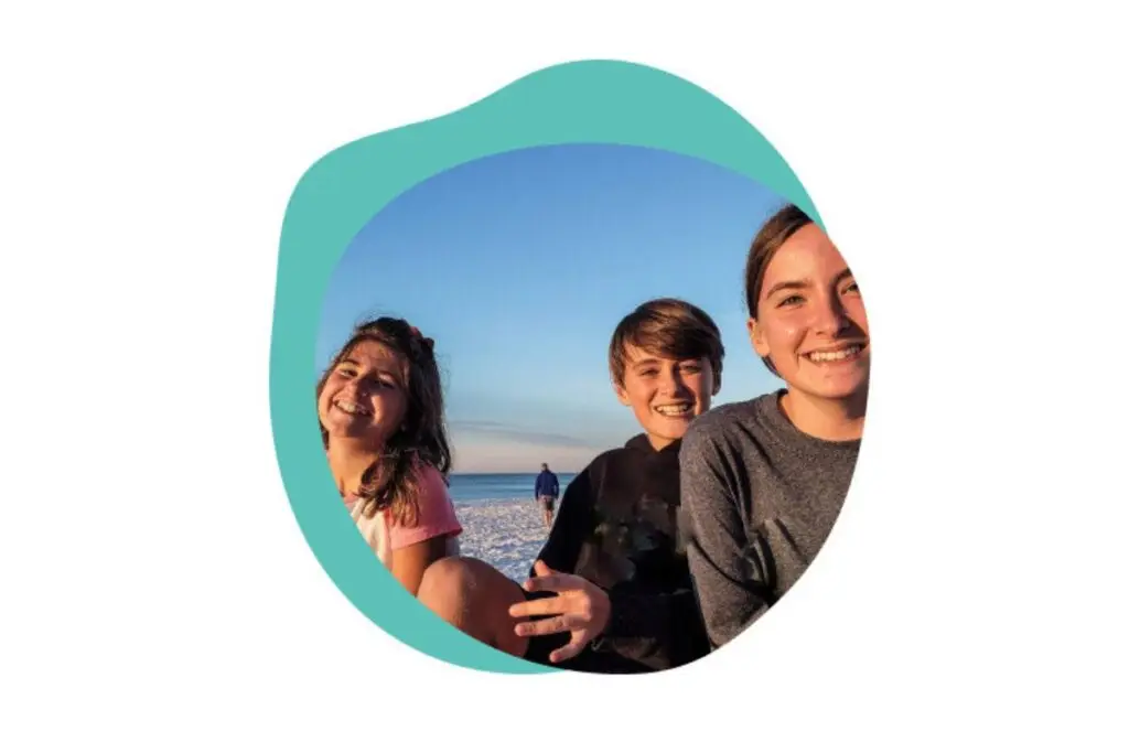 Three happy children sitting on a beach.