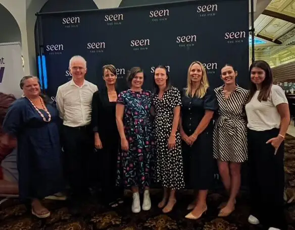 8 people standing in front of a SEEN banner including QKP staff members