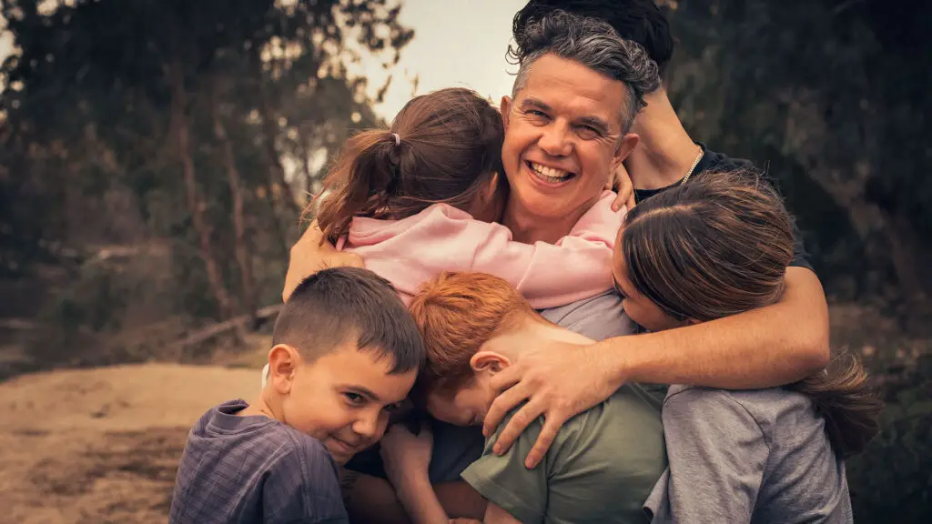 Smiling father hugging four children